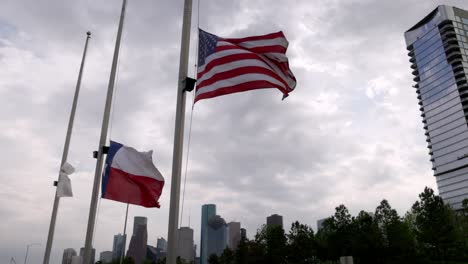 Bandera-Americana-Y-Bandera-Del-Estado-De-Texas-Ondeando-En-El-Viento-Con-Un-Edificio-En-El-Fondo-En-Houston,-Texas-Con-Video-Estable