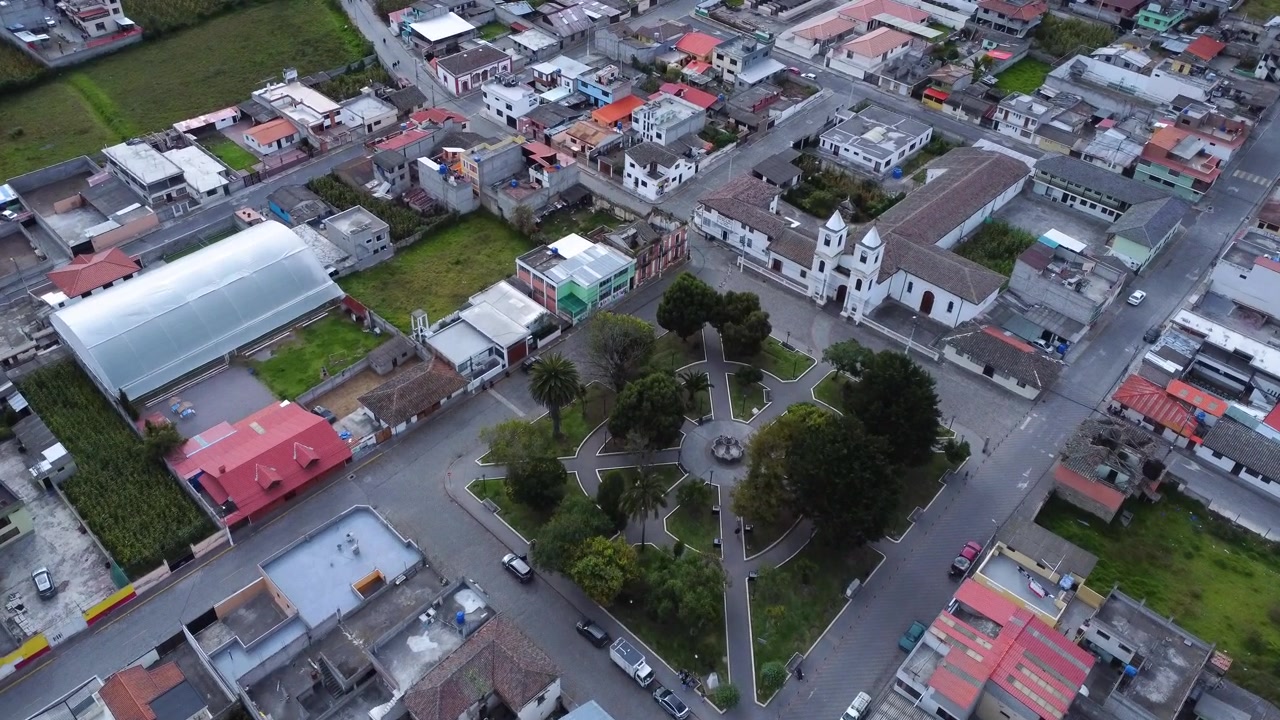 Drone che avanza verso il monumento e la chiesa della Mitad del Mundo sopra la piazza centrale di Calacali in Ecuador.
