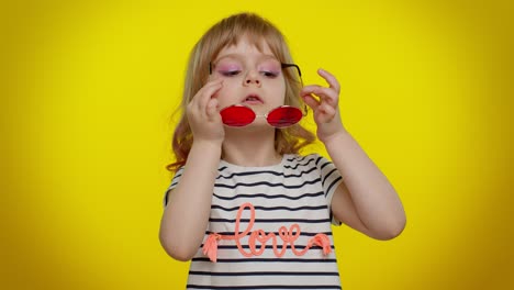 Portrait-of-funny-playful-blonde-child-girl-in-striped-t-shirt-wearing-sunglasses,-charming-smile