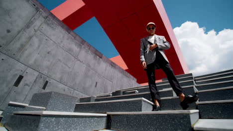 stylish man posing on modern concrete stairs with red architecture