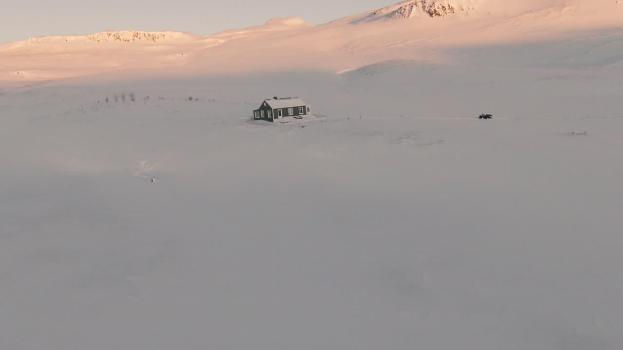 Orbit around frozen cabin in snowy mountains during sunset