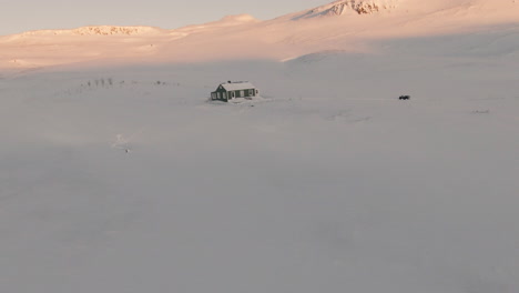 Orbita-Alrededor-De-Una-Cabaña-Congelada-En-Montañas-Nevadas-Durante-La-Puesta-De-Sol