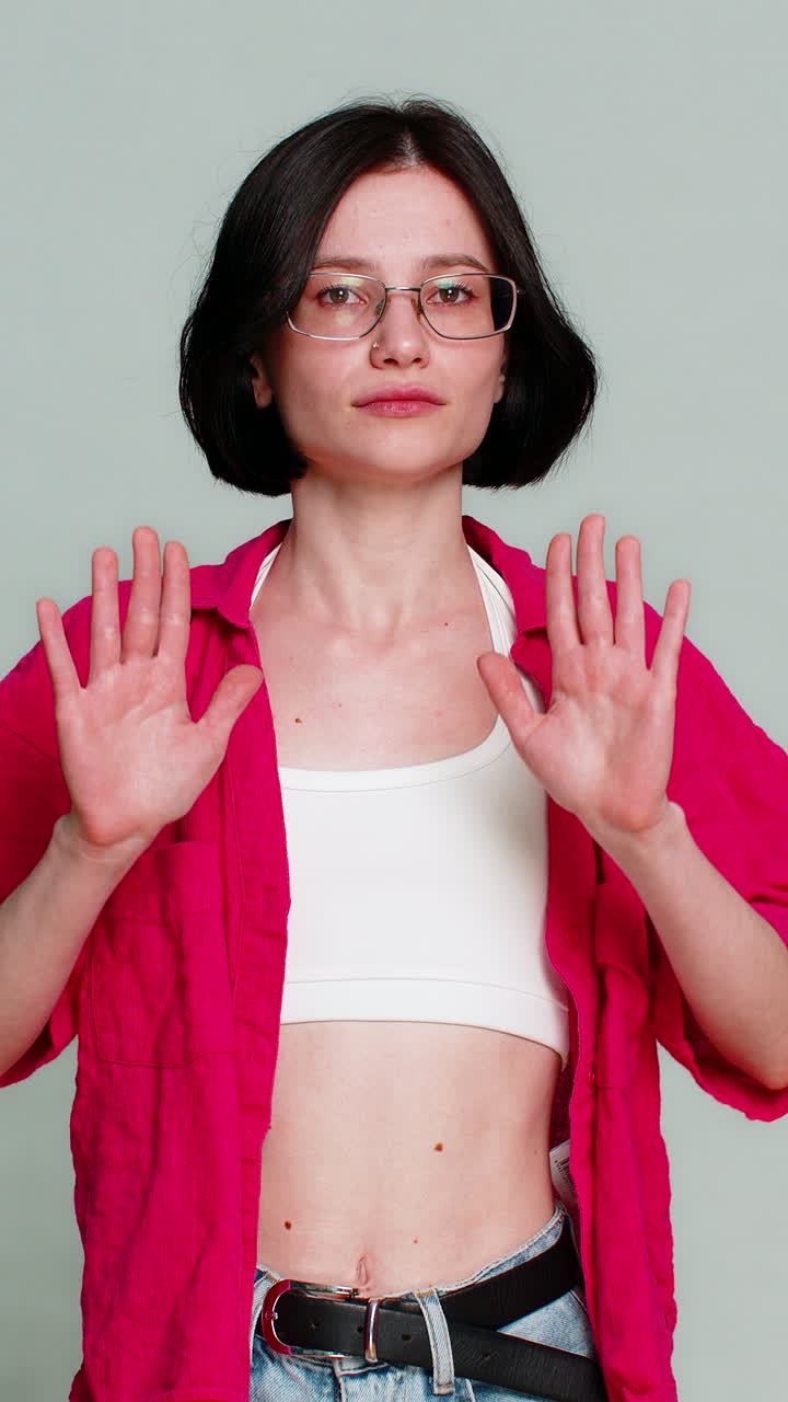Young woman showing careful warning gesture with serious facial expression cautioning viewer beware