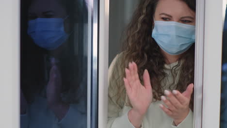 woman clapping through window during pandemic