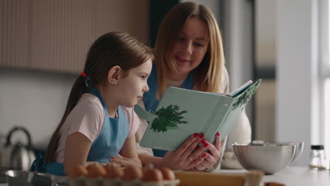 madre y hija están cocinando pastel en la cocina de la casa leyendo el recibo en el libro de cocina mujer adulta y niña pequeña