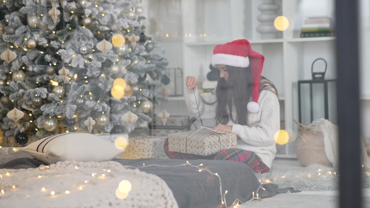 mujer abriendo el regalo de navidad junto al árbol de navidad