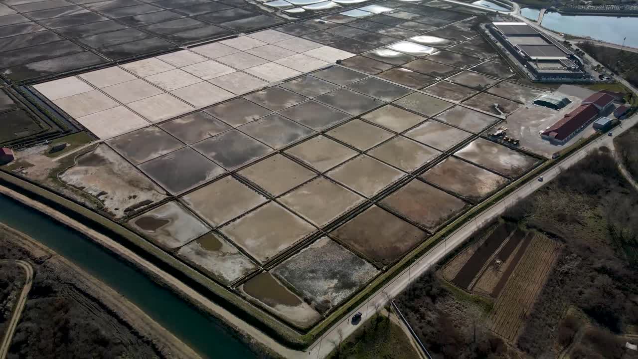 Volo di drone all'indietro accanto a una salina in Croazia, nella città di Nin, con strada e alcune auto di giorno