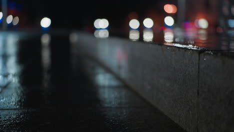 blurred view of cars passing with headlights on a wet city street at night, creating vibrant light reflections