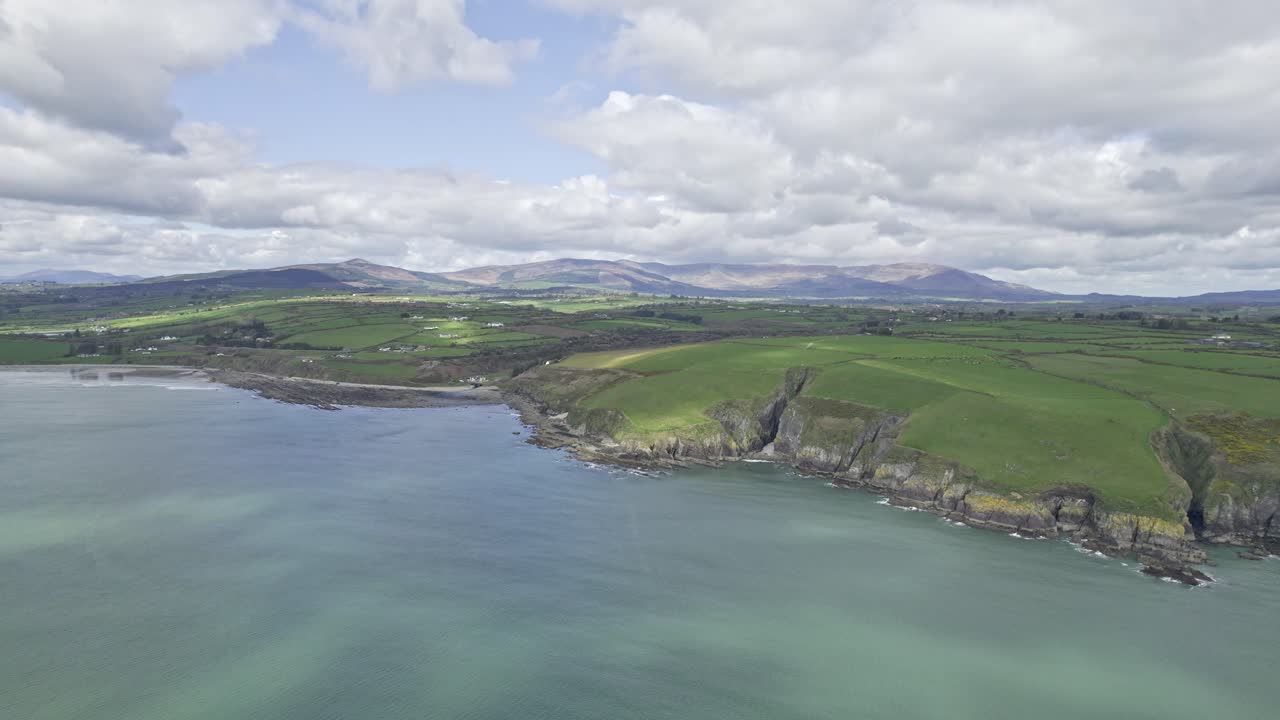 aerial acercándose a la costa de waterford con las montañas de comeragh en el fondo en un cálido día de primavera