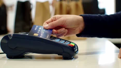 a close-up view of a payment terminal as a customer makes a transaction with a credit card in a retail environment, highlighting modern payment methods