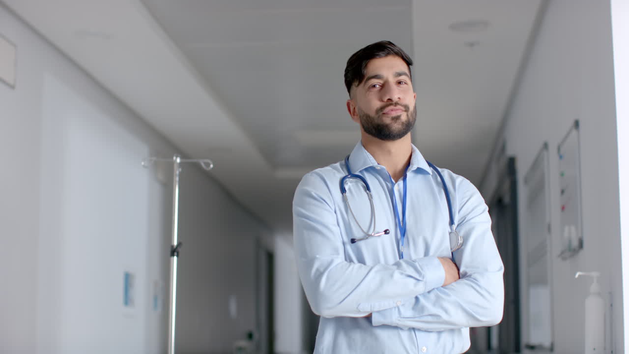 Retrato de médico birracial con bata de laboratorio en el pasillo del hospital, espacio para texto, en cámara lenta.