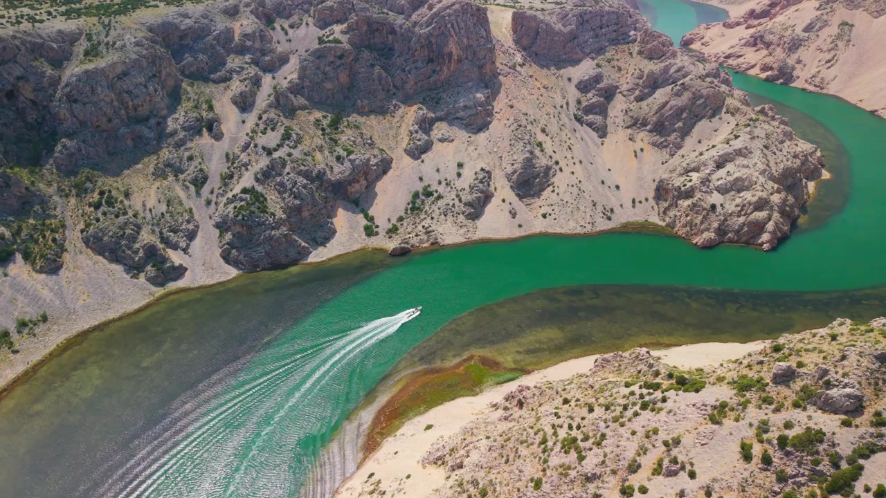 Vista aerea mozzafiato dell'ansa del canyon del fiume Zrmanja con un motoscafo che naviga acque color smeraldo in Croazia