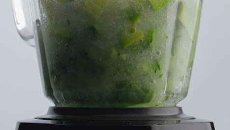 vegetales de primer plano mezclando agua dentro del cuenco de la licuadora en súper cámara lenta.