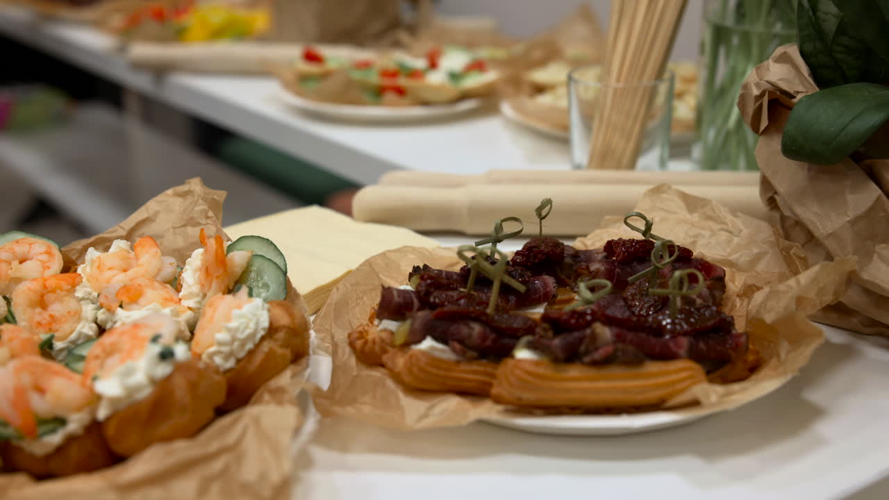 Piatto di salumi e bruschette ai gamberi sul tavolo, crostini avvolti in carta forno conditi con gamberi e crema alle erbe