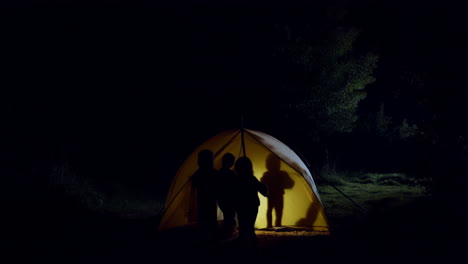 silhouettes of children playing in an illuminated tent at night