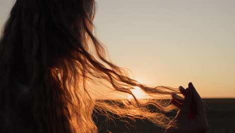 teen looks at her hair in the sun, holds a lock of hair in her hand