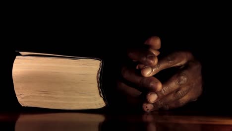 Beten-Zu-Gott-Mit-Den-Händen-Zusammen-Mit-Bibel-Karibischer-Mann-Beten-Mit-Schwarzem-Hintergrund-Stock-Video
