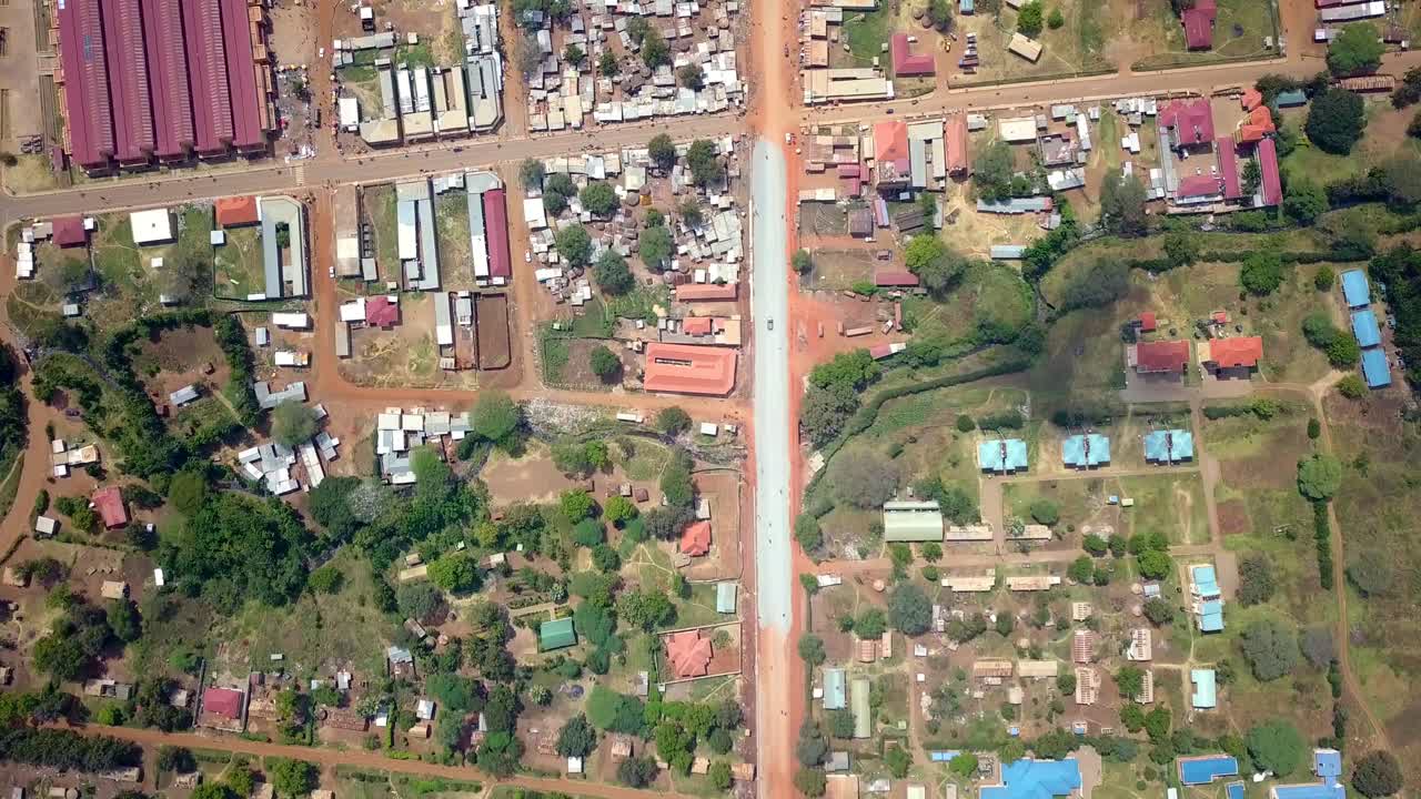 Aerial view of Moroto town, Uganda, showcasing a developing urban scape with a major road dividing residential and commercial areas, reflecting regional growth and infrastructure, drone overhead shot