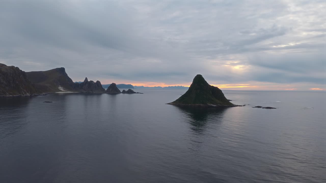 A calm, aerial shot of rugged coastal peaks and islands at Vestarelens, Norway