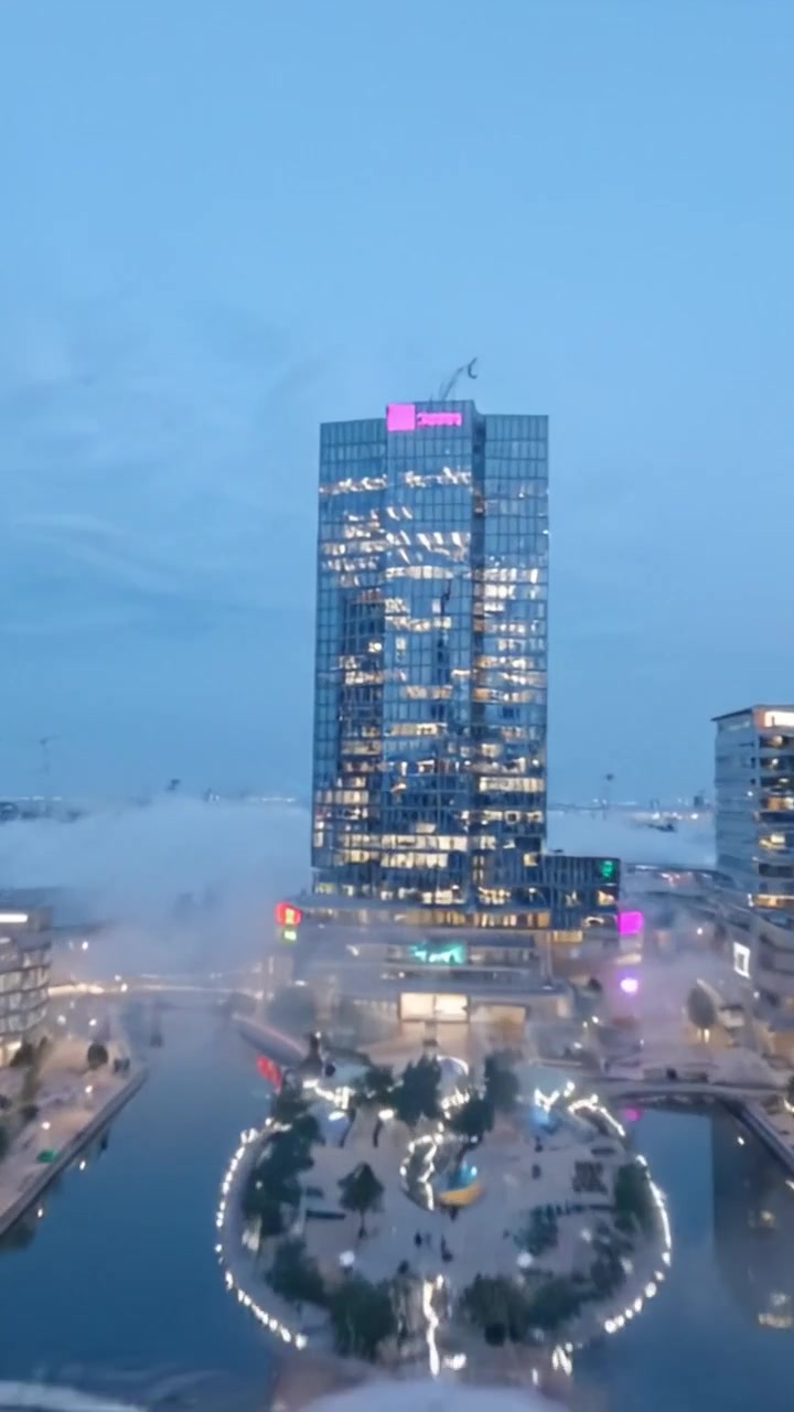 Vista Dramática de Estruturas Urbanas Iluminadas ao Anoitecer, Exibindo Arquitetura Moderna e Cores Vibrantes com um Reflexo Fascinante na Água