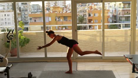 mujer practicando yoga en un apartamento con vistas a la ciudad