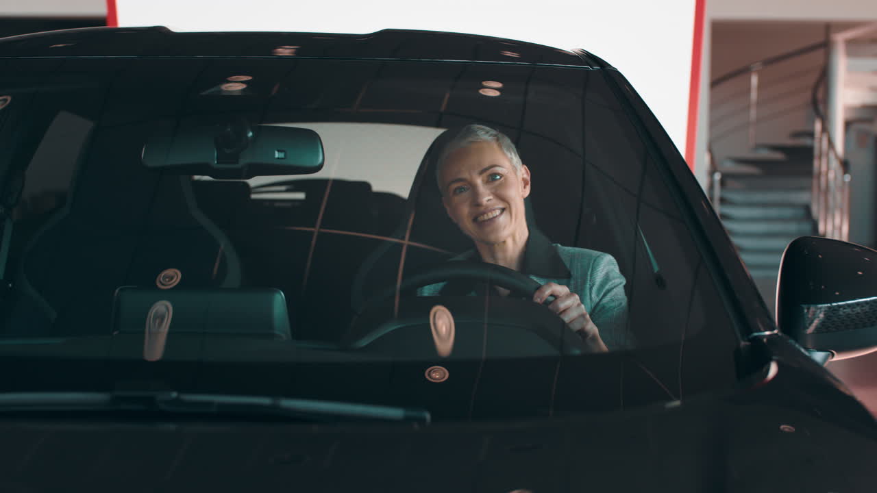 mujer de prueba conduciendo un nuevo coche negro en una sala de exposiciones