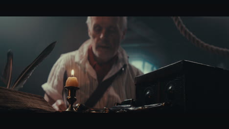 an old captain sits writes a letter inside the sailing ship cabin