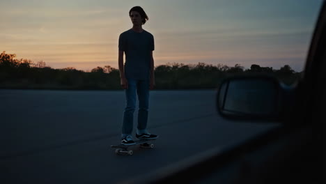 Young Man Skateboarding on an Empty Road at Sunset