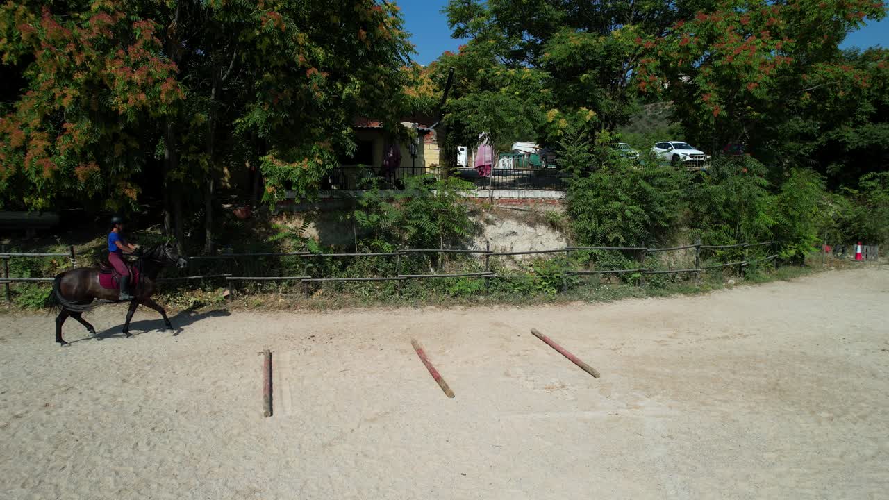 Slow motion static aerial captures a rider walking slowly in the arena when the trainer suddenly appears nearby