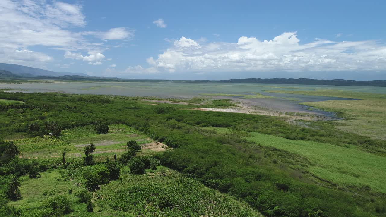 volando sobre tierras de cultivo cerca de un lago rodeado de hermosas montañas y nubes blancas esponjosas, laguna ca drone antena