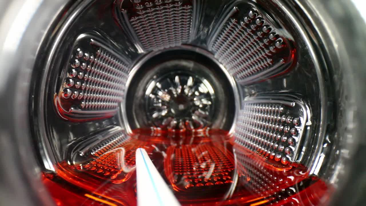 İçinde beyaz pipet ve kırmızı sıvı bulunan bir spor içeceği veya meyve suyu şişesinin altından tamamen dışarı çıkan çekim.