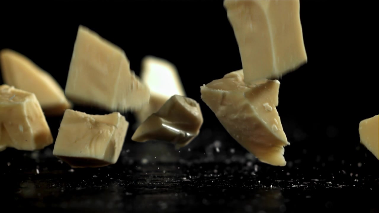 White Chocolate Chunks Falling in Slow Motion on Black Background