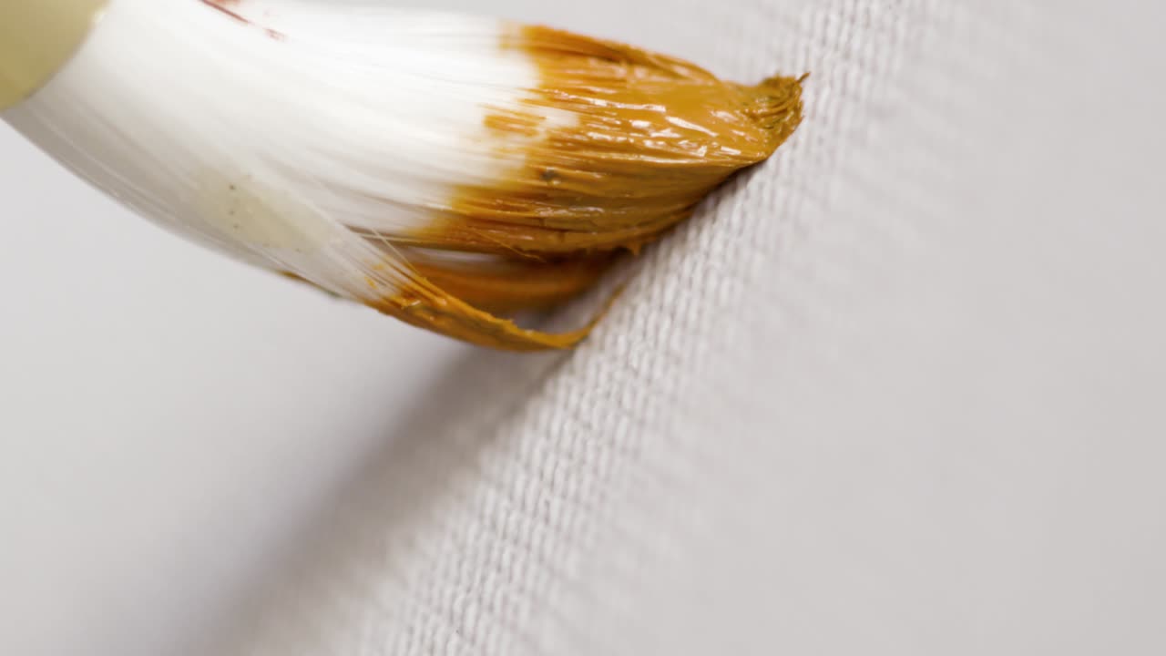 pincel para aplicar pintura amarilla en el lienzo