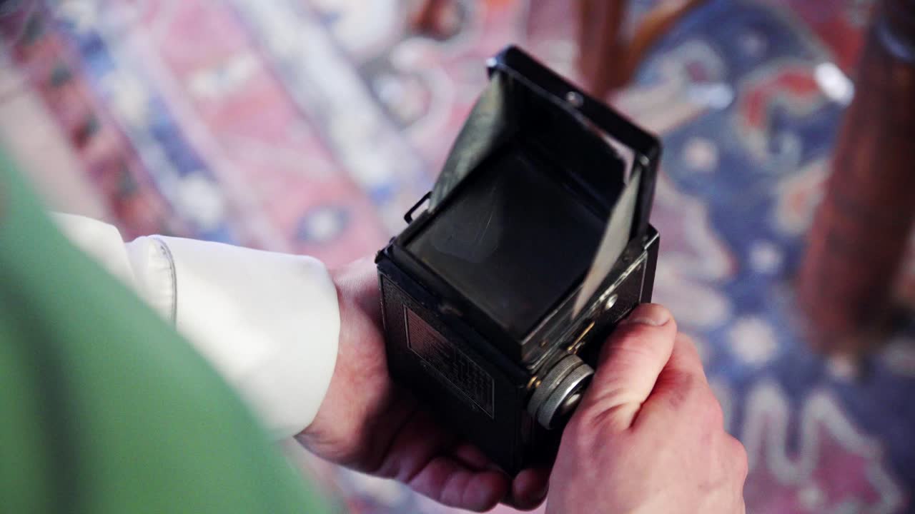 Elf photographing. Retro camera in man's hands. Elf is setting up retro camera. Close-up