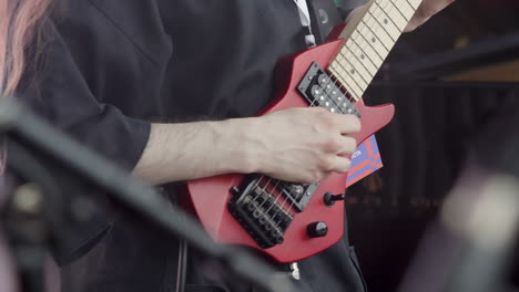 person playing a red electric guitar