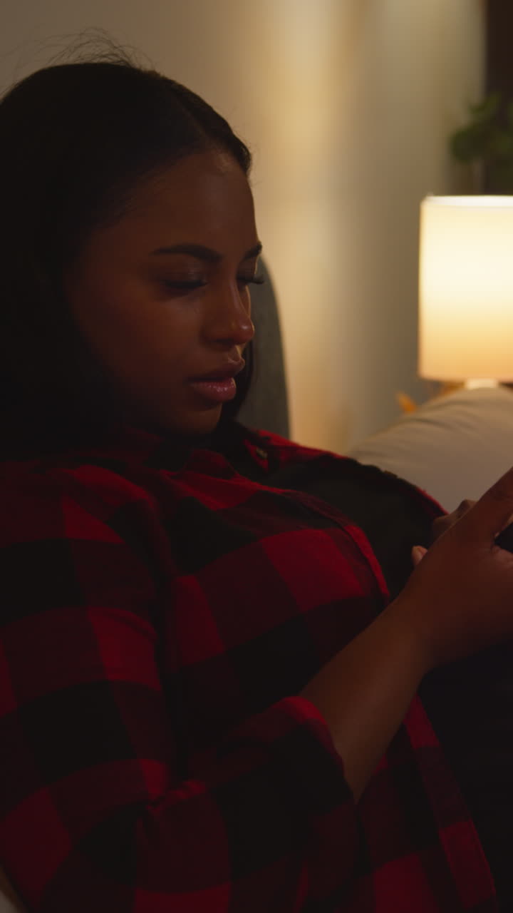 Kvinde bruger smartphone på en sofa om natten