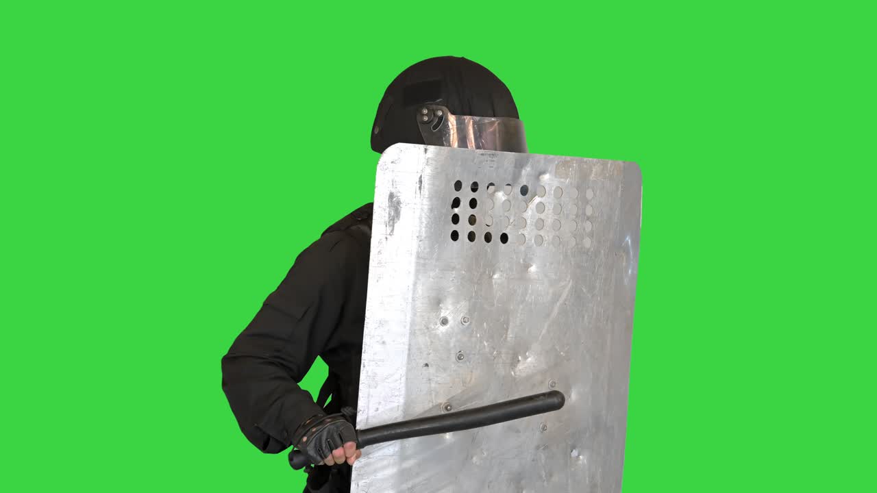 Riot Police unit holding position covering with a shield and holding a baton on a Green Screen, Chroma Key