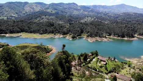 Szenische-Luftaufnahme-Nach-Vorne-über-Bäume-Und-Die-Lagune-Von-Guatape,-Kolumbien