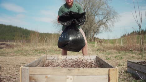 view of a man putting soil in wooden planter - wide