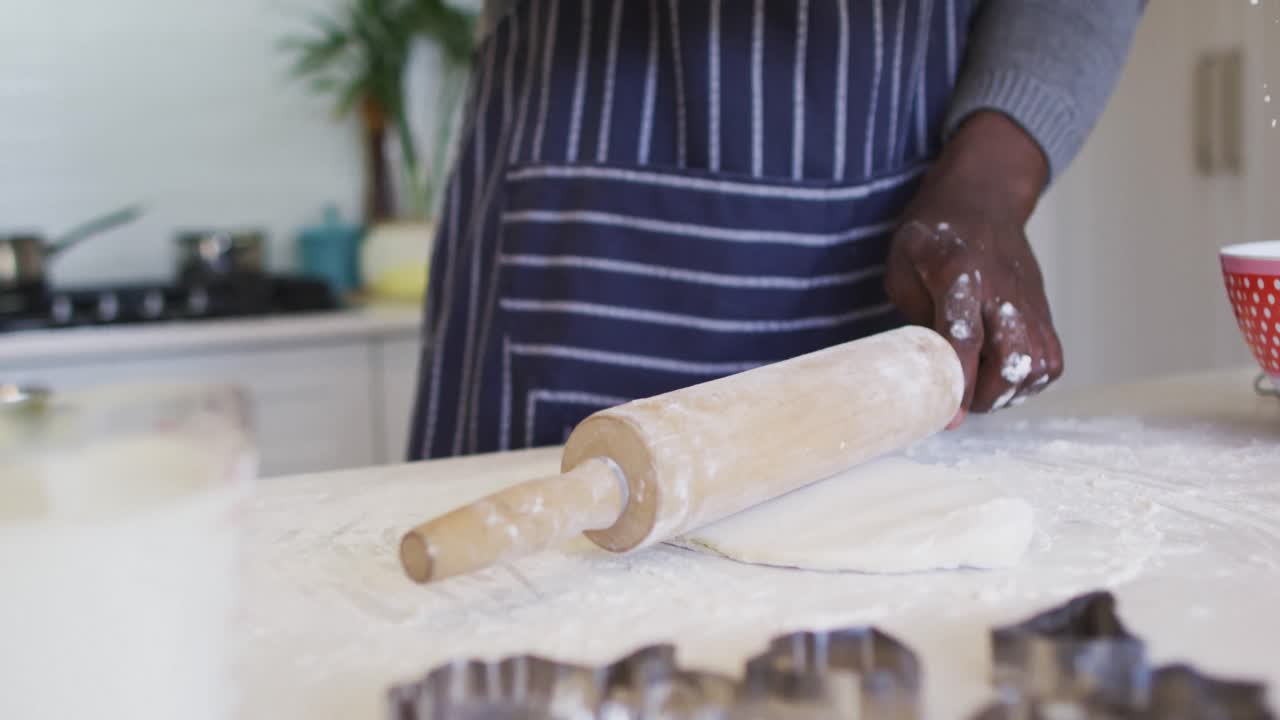 Hands of african american man using flour, preparing dough in kitchen