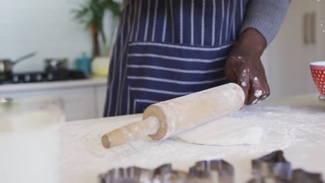 hands of african american man using flour, preparing dough in kitchen