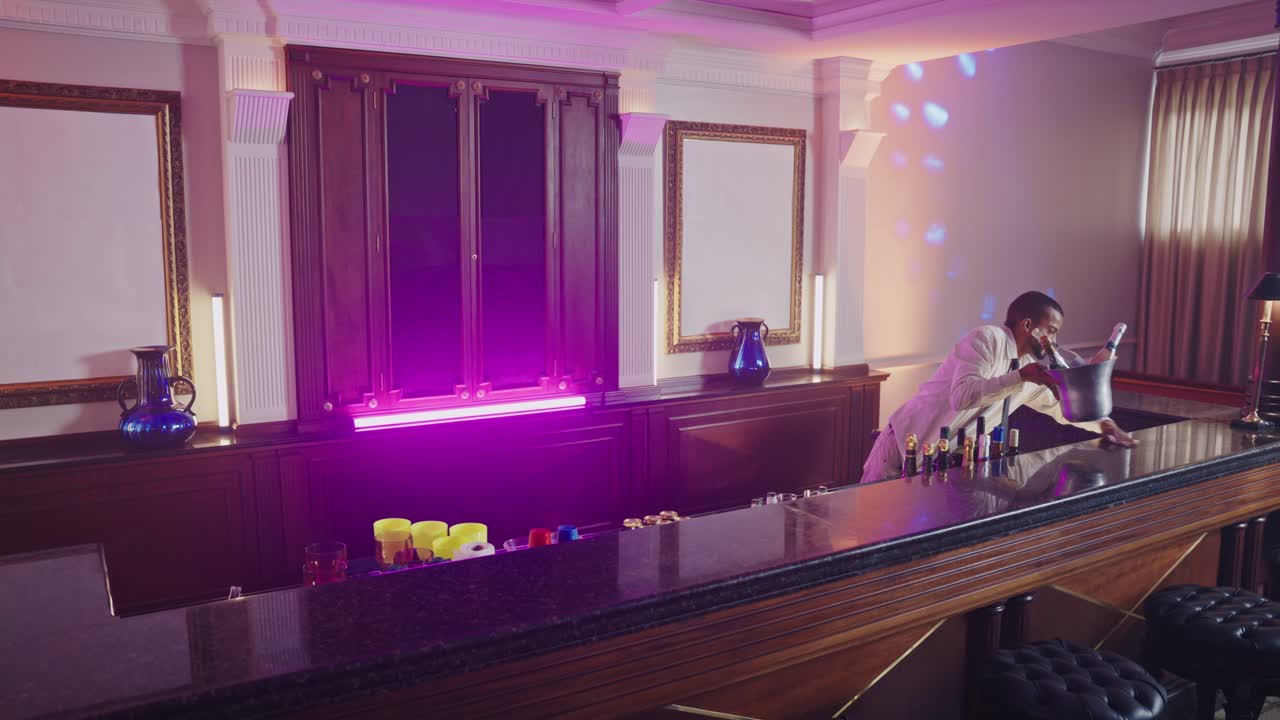 A bartender working and preparing drinks in a vibrant, neon-lit bar