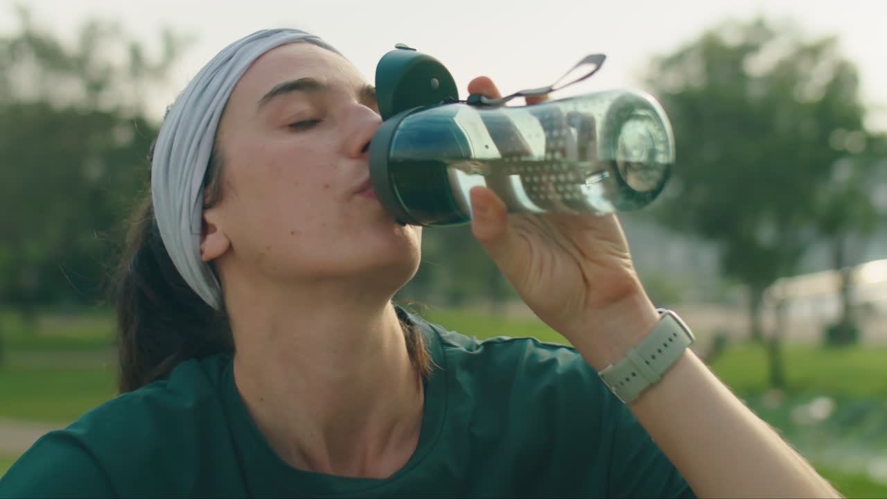 Woman Drinking Water after Outdoor Training in Park