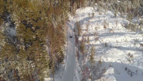 一片雪<unk>的松树林和一条在白天驾驶汽车的道路的空中景色 - 无人机拍摄