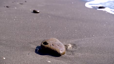 Single,-isolated-rock-on-beach-with-breaking-waves-in-background