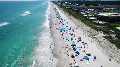 beautiful drone footage at the beach with turquoise ocean waters and people on the shore