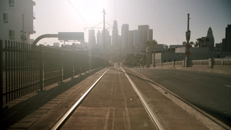 train tracks leading towards a hazy city skyline