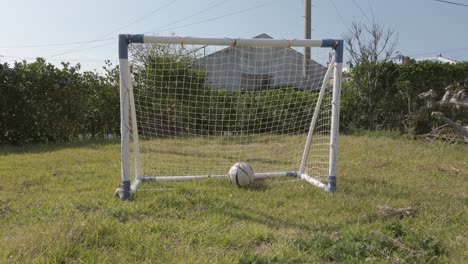 Pelota-De-Fútbol-Pateada-Y-Volando,-Luego-Rueda-Hacia-Una-Pequeña-Red-De-Portería