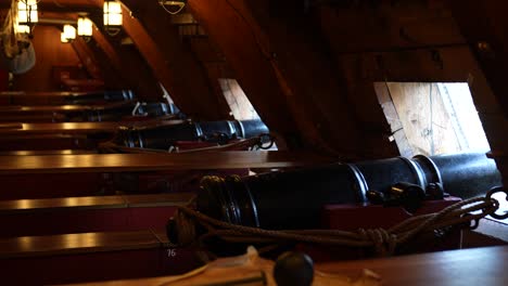 close up of metal cannons below deck of a wooden old warship