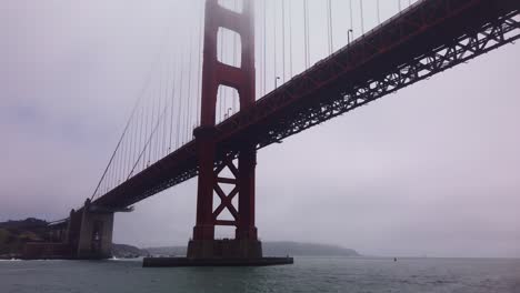 gimbal close-up shot from a moving boat as it passes underneath the golden gate bridge on a foggy day in san francisco, california